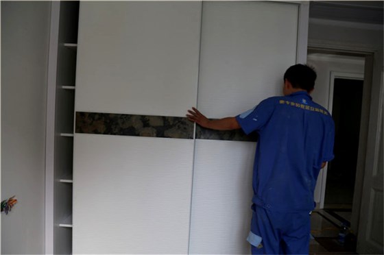左右手家具安裝師傅在實(shí)木衣柜安裝完后正在調(diào)試衣柜門(mén)